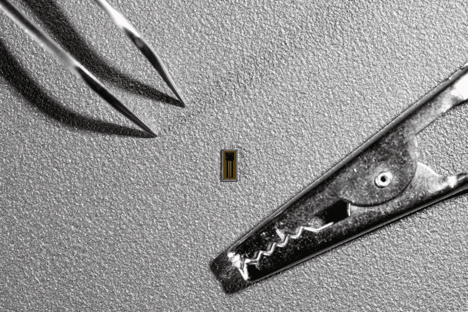 The new small MiBMI chip next to a pair of tweezers and an alligator clip for comparison

(Credit: EPFL)